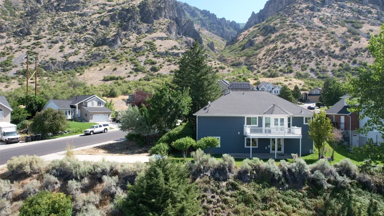 Two-story residence featuring a blue exterior, a second-story balcony with white railings, and a lower-level patio