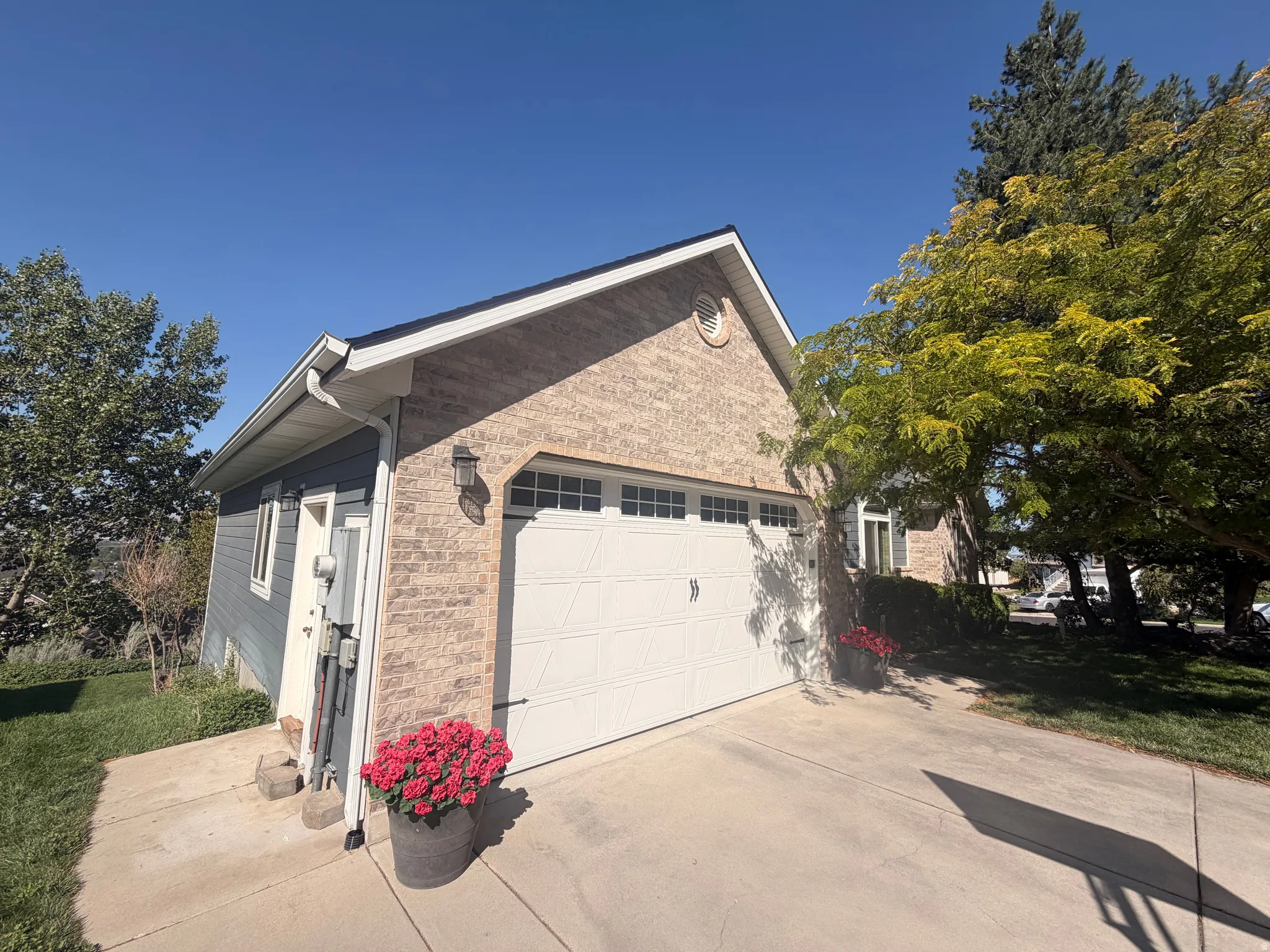 Attached garage with a white panel door, brick facade, and a circular vent feature