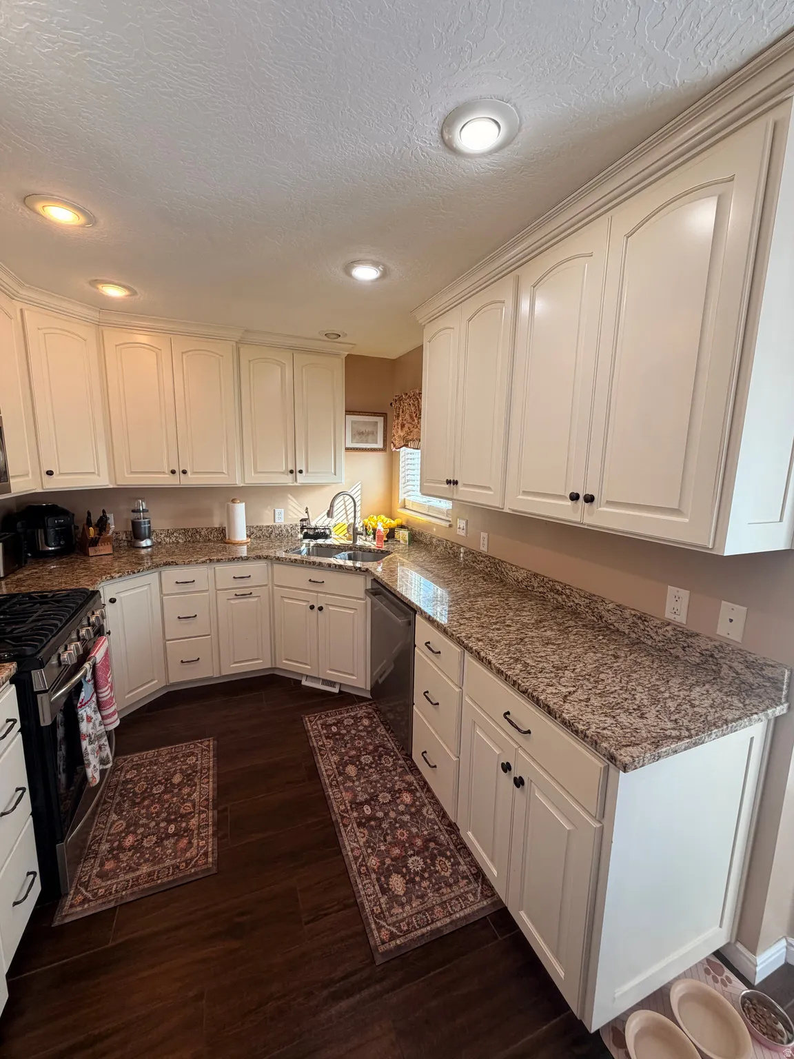 Kitchen featuring extensive white cabinetry, granite-finish countertops, wood-finish flooring, recessed lighting, and a stainless steel appliance suite