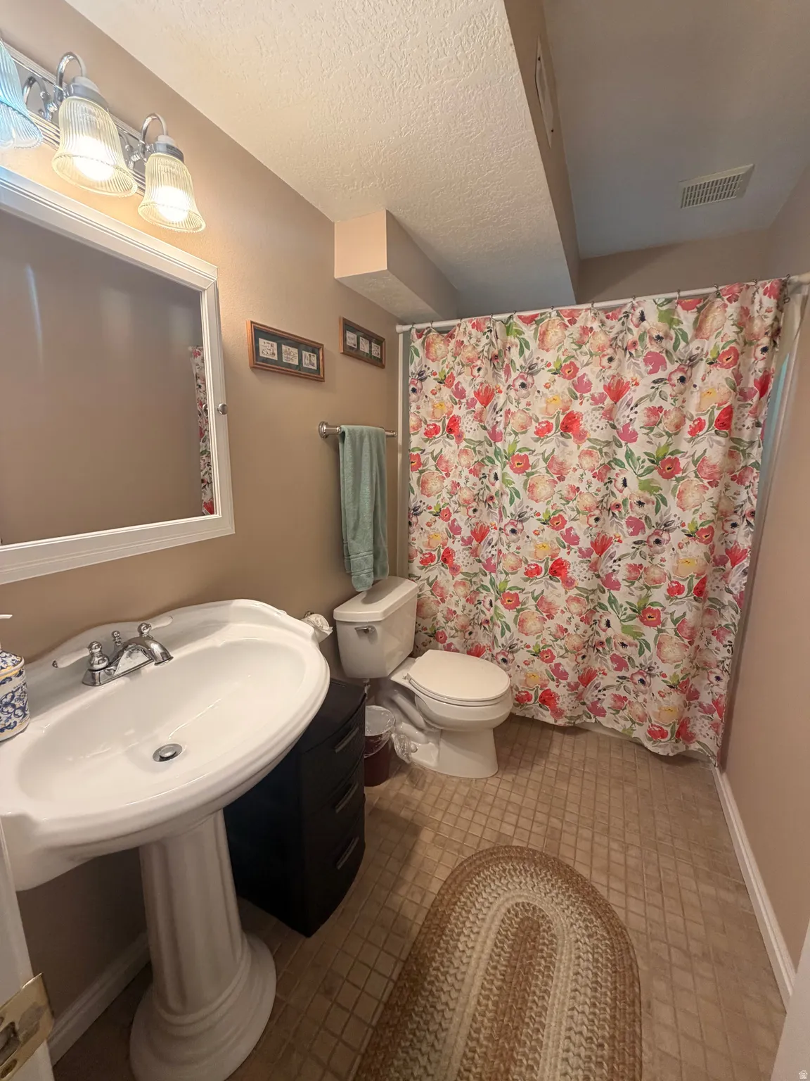 Pedestal sink with chrome fixtures, vanity mirror, and overhead lighting