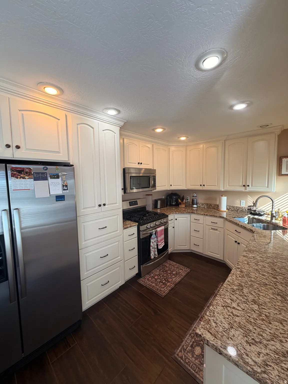 Kitchen featuring white cabinetry, stainless steel appliances, granite countertops, wood-finish flooring, and recessed lighting