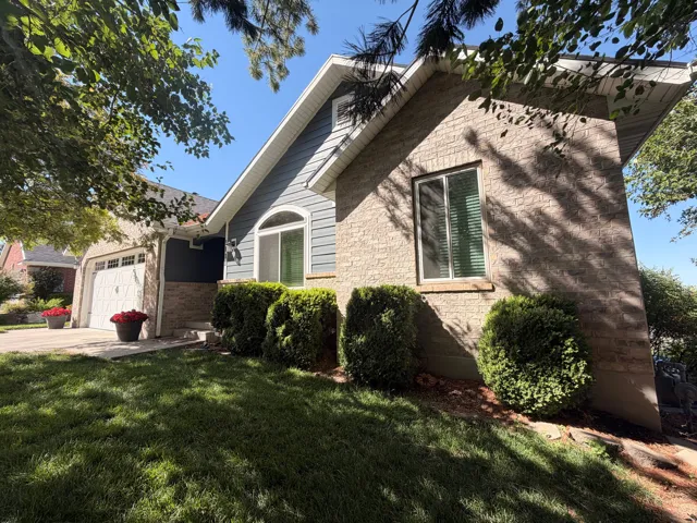 Exterior featuring brick and horizontal siding, an arched window, a two-car garage, and established perimeter landscaping