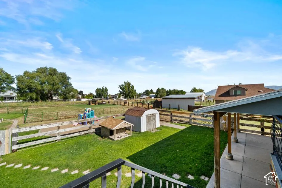Expansive fenced yard featuring a grassy area, concrete patio, and mature trees