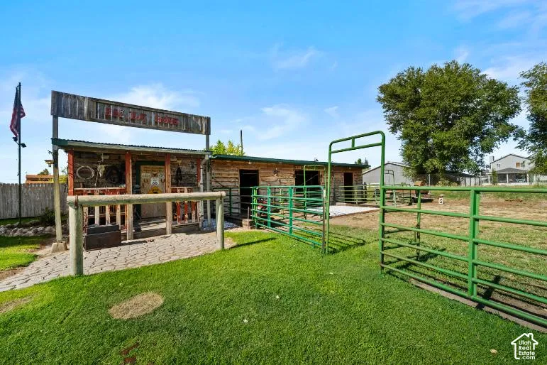 Fenced outdoor area with a rustic-style building featuring a covered porch and an adjacent log-style structure