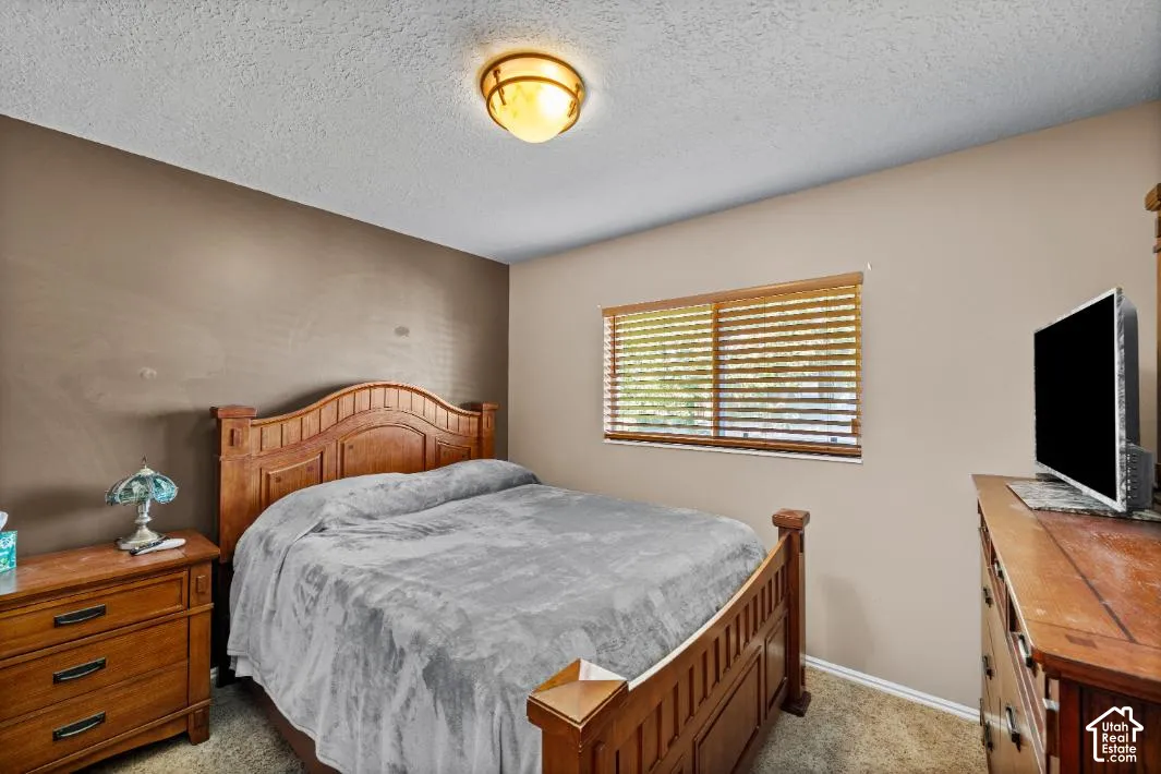 Comfortable secondary bedroom showcasing warm wood-finish furnishings, neutral wall tones, and natural light from shuttered windows