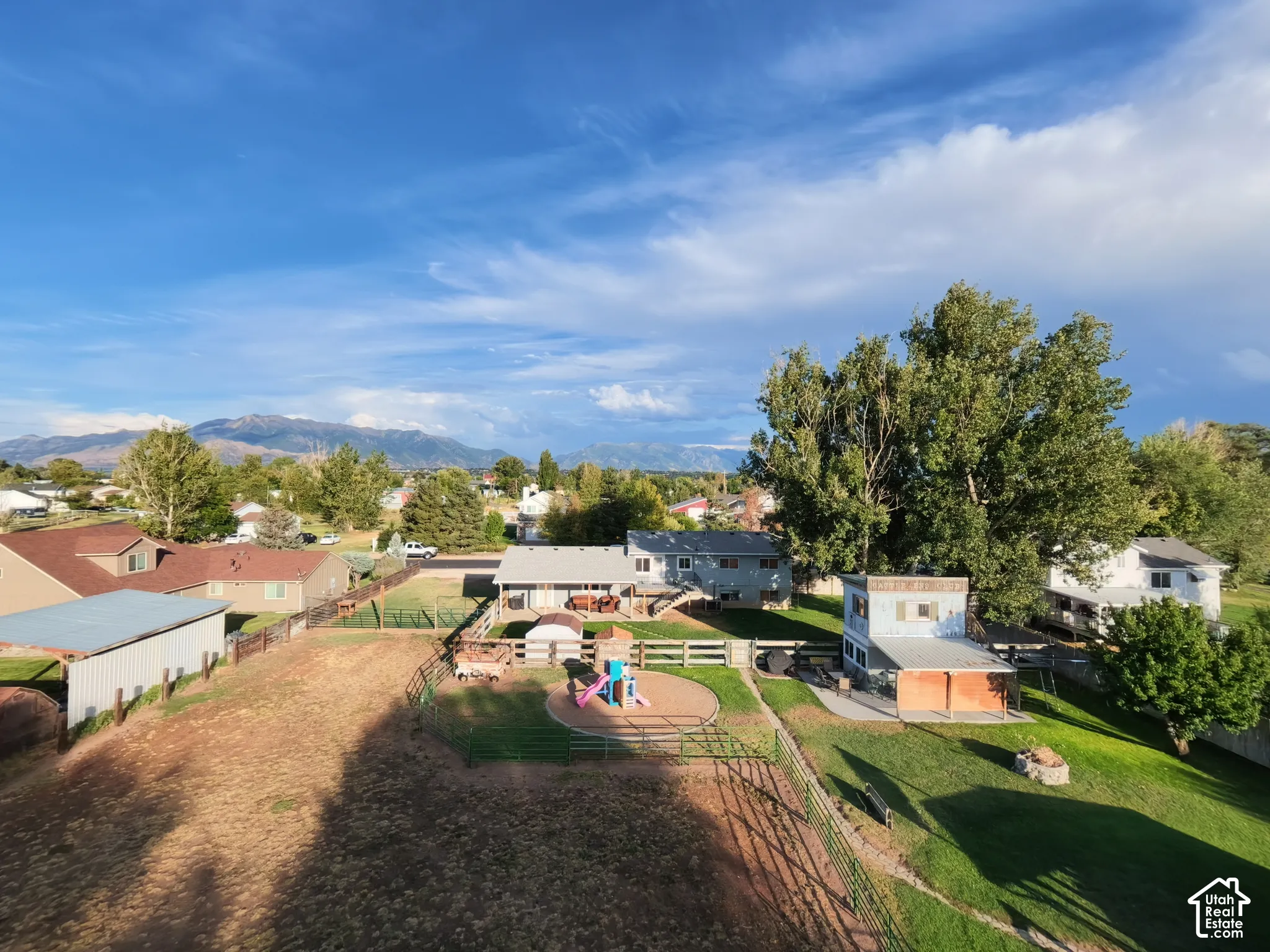 Expansive property featuring a large open field, fenced yard areas, and a detached outbuilding