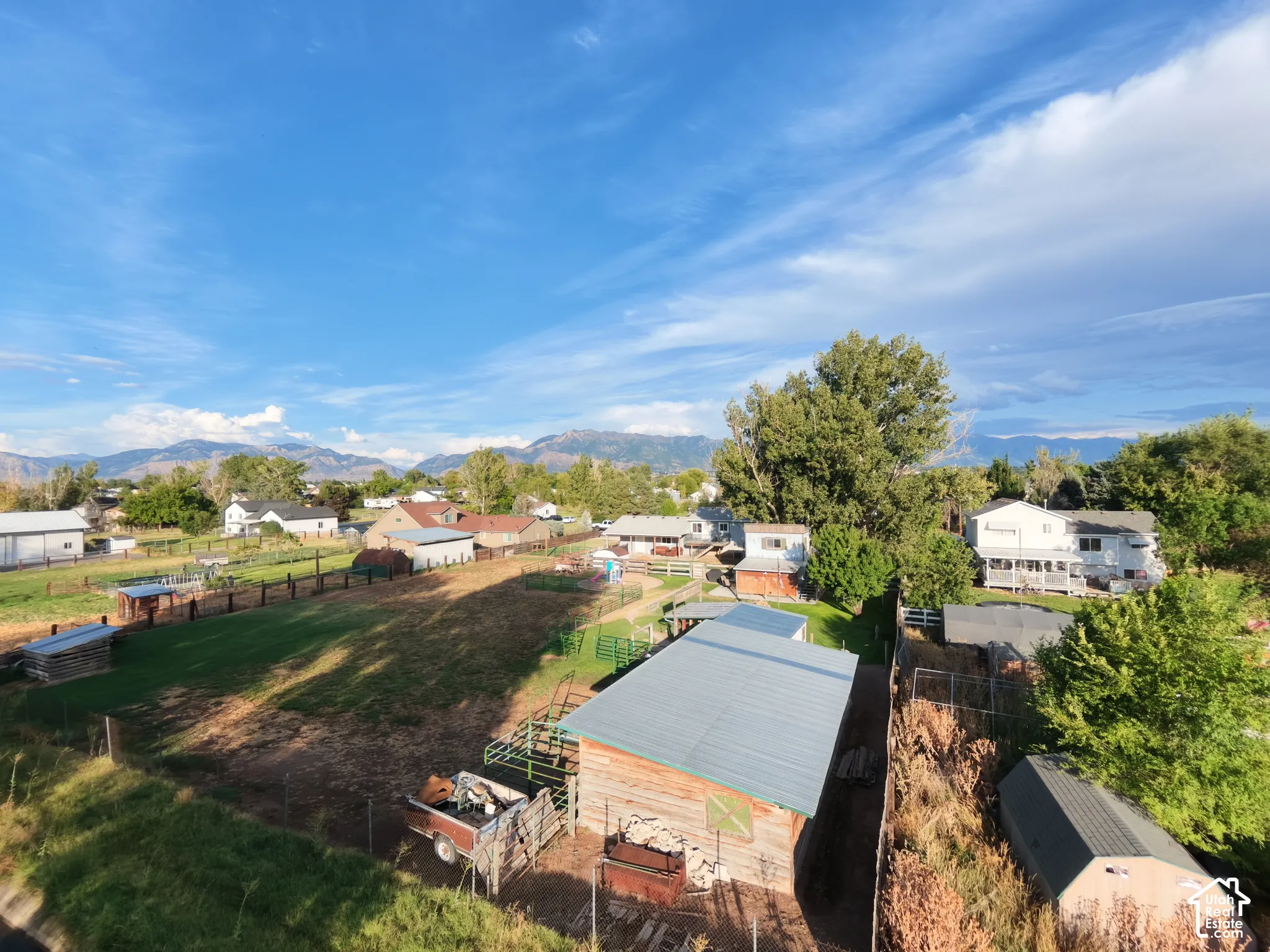 Expansive property featuring multiple outbuildings, fenced areas, and distant mountain backdrops