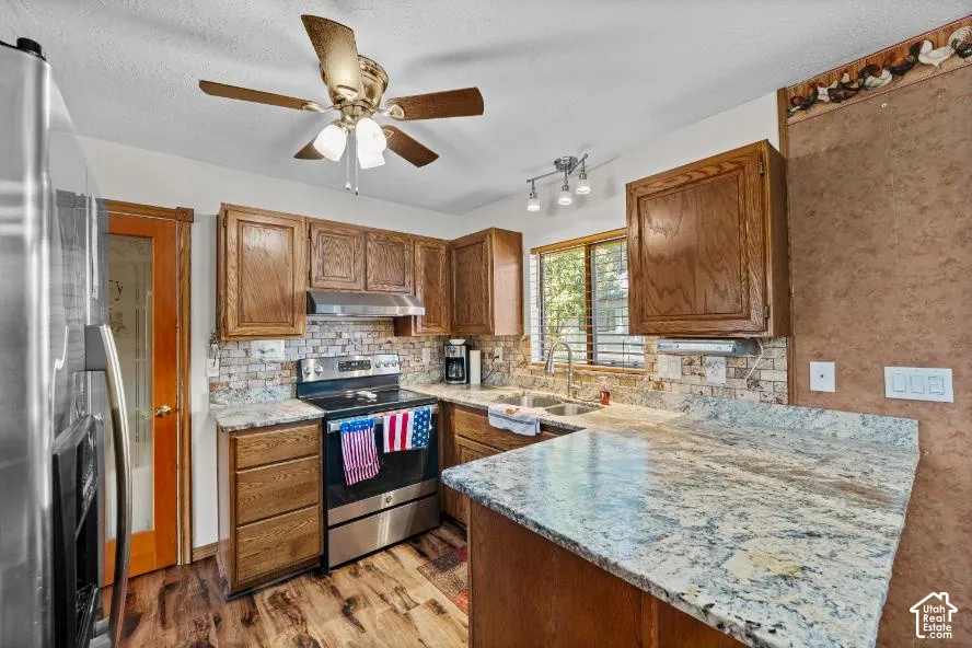 Kitchen featuring wood-finish flooring, wood cabinetry, stone countertops, and a tiled backsplash