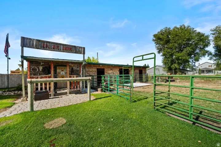 Fenced outdoor area with a rustic-style building featuring a covered porch and an adjacent log-style structure