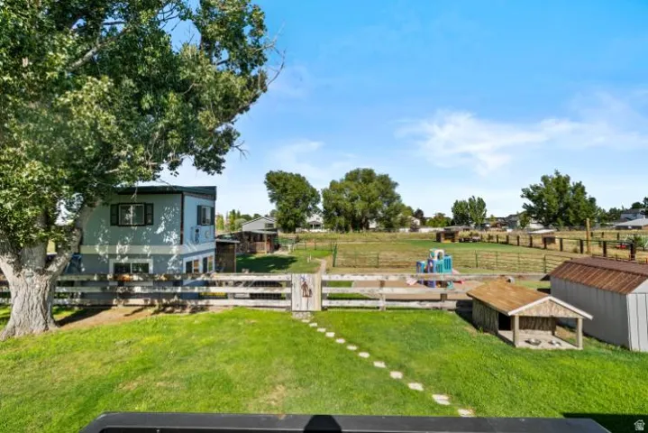 Expansive backyard featuring a manicured lawn, established shade tree, and wooden fence
