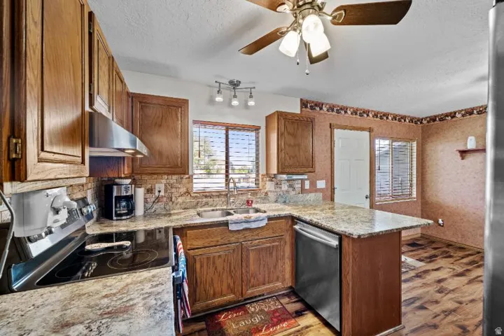 Spacious kitchen featuring warm wood cabinetry, granite countertops, stainless steel appliances, a center island with additional storage, and tile flooring
