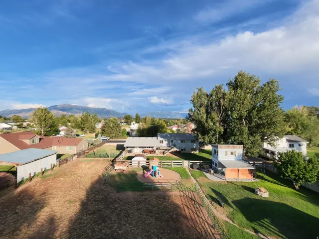 Expansive property featuring a large open field, fenced yard areas, and a detached outbuilding