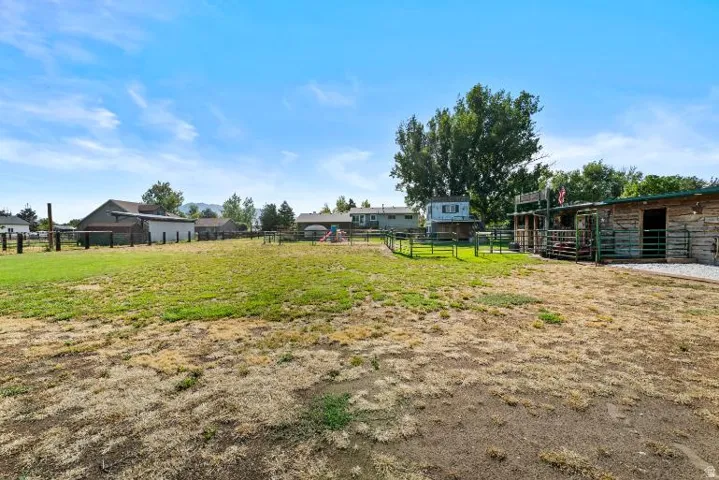 Expansive outdoor space featuring a barn structure, a fenced animal enclosure, and a gravel pathway