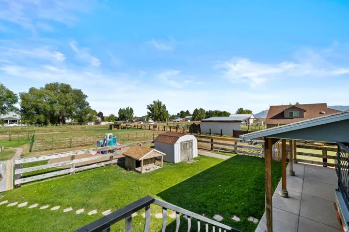 Expansive fenced yard featuring a grassy area, concrete patio, and mature trees