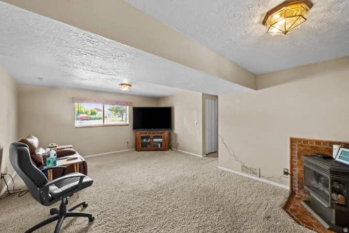 Carpeted living space featuring a window, built-in light fixtures, and a corner fireplace with a tiled surround