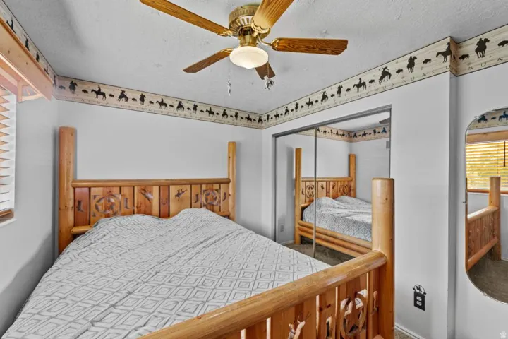 Ceiling fan with integrated lighting, mirrored sliding closet doors, and wood-framed window with blinds