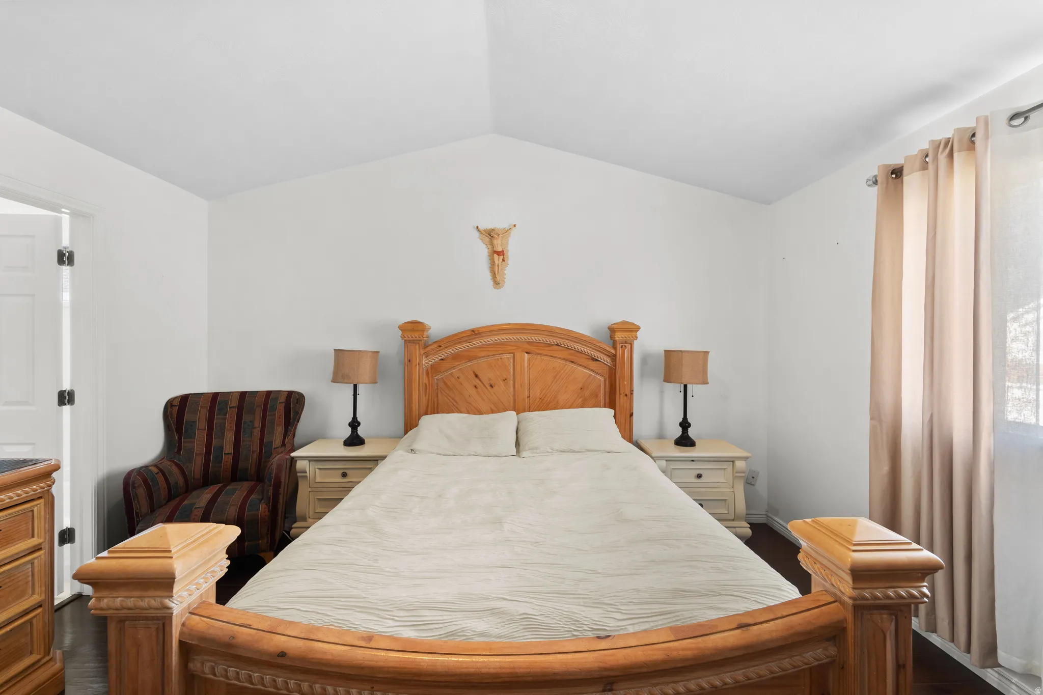 Vaulted ceiling, white walls, dark wood-finish flooring, recessed window, and a white paneled door