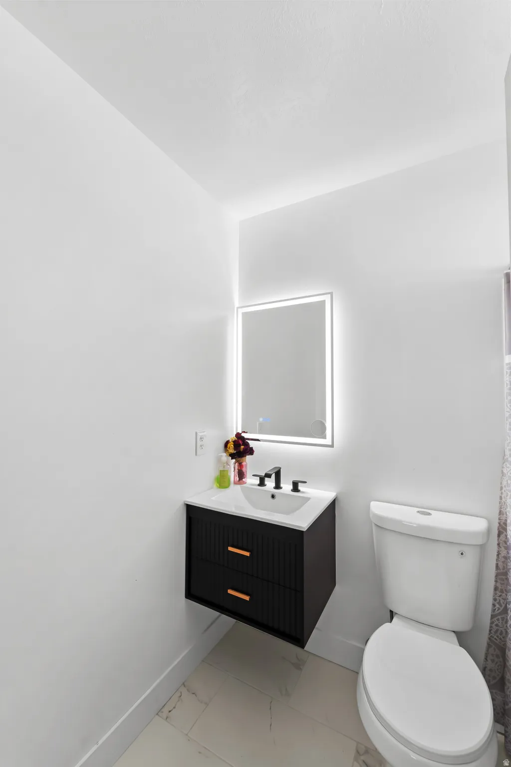 Floating vanity with textured black cabinetry, white countertop, and integrated sink
