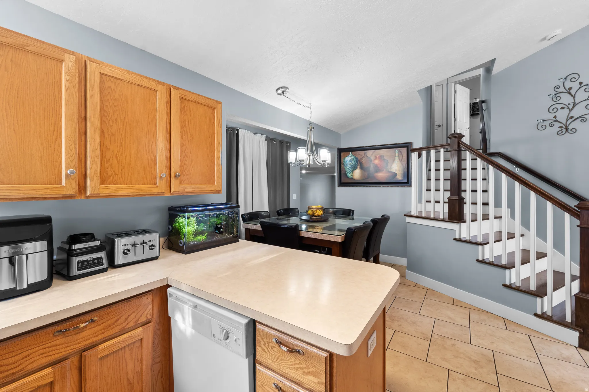Kitchen featuring wood cabinetry, light-toned countertops, and a built-in dishwasher