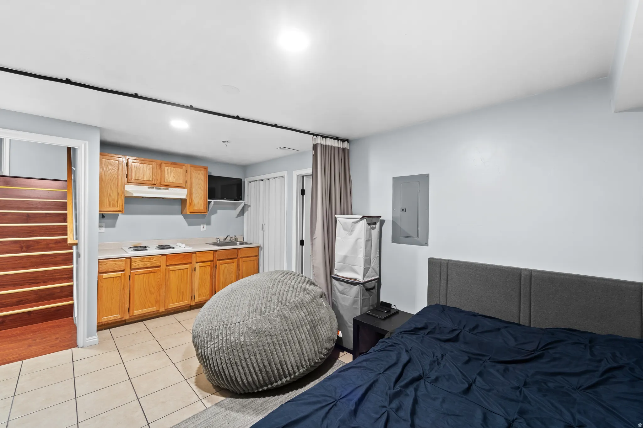 Compact kitchen area with wood-finish cabinetry, light-toned countertop, and tile flooring