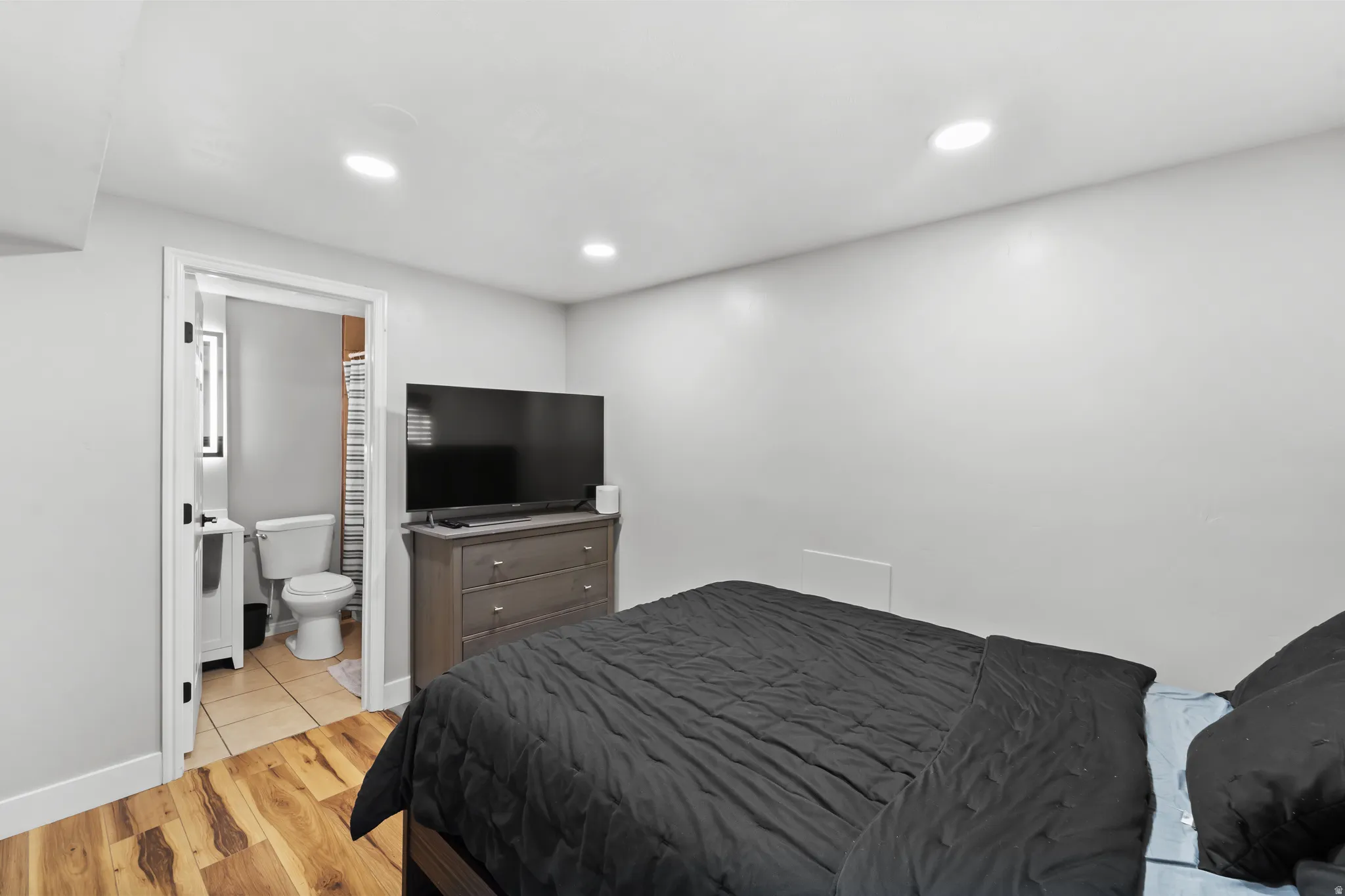 Recessed ceiling lighting illuminates the room with wood-finish flooring