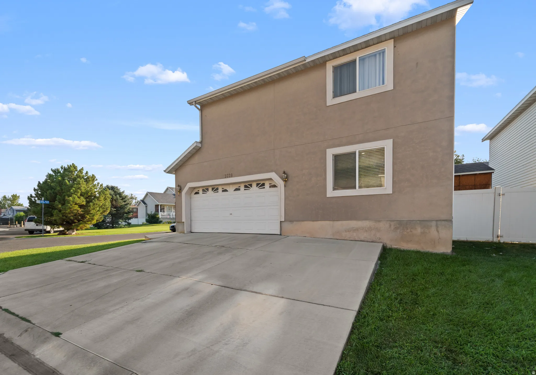 Stucco exterior with white trim windows, an attached garage, and a concrete driveway