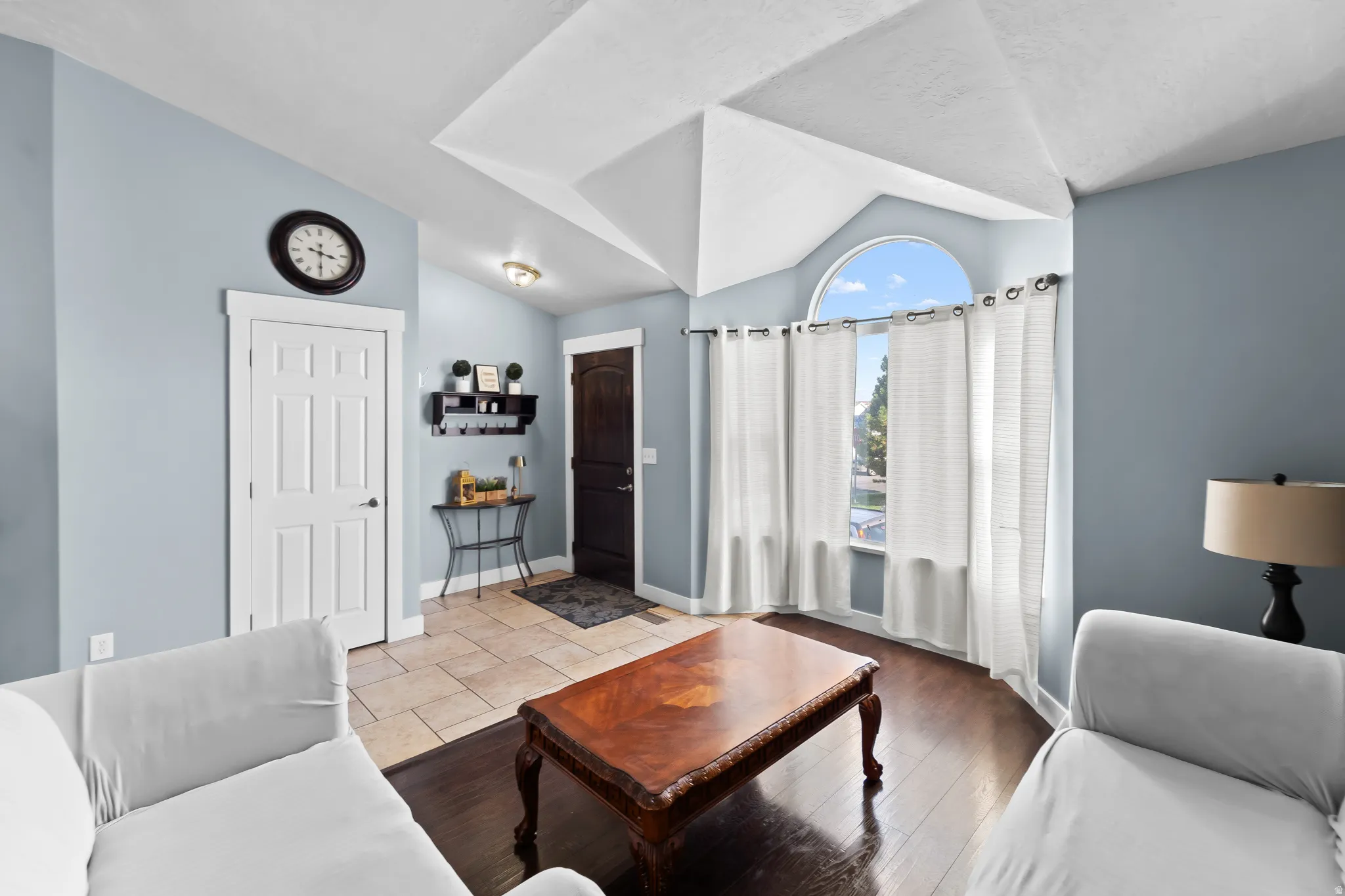 Vaulted ceiling, arched window, wood-finish flooring, tiled entry, and five-panel interior doors