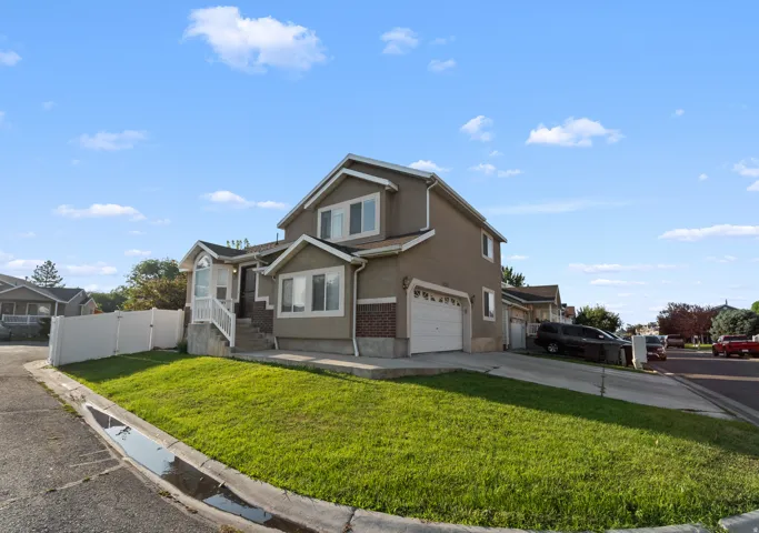 Multi-level property featuring a two-car garage, bay window, and a white fence