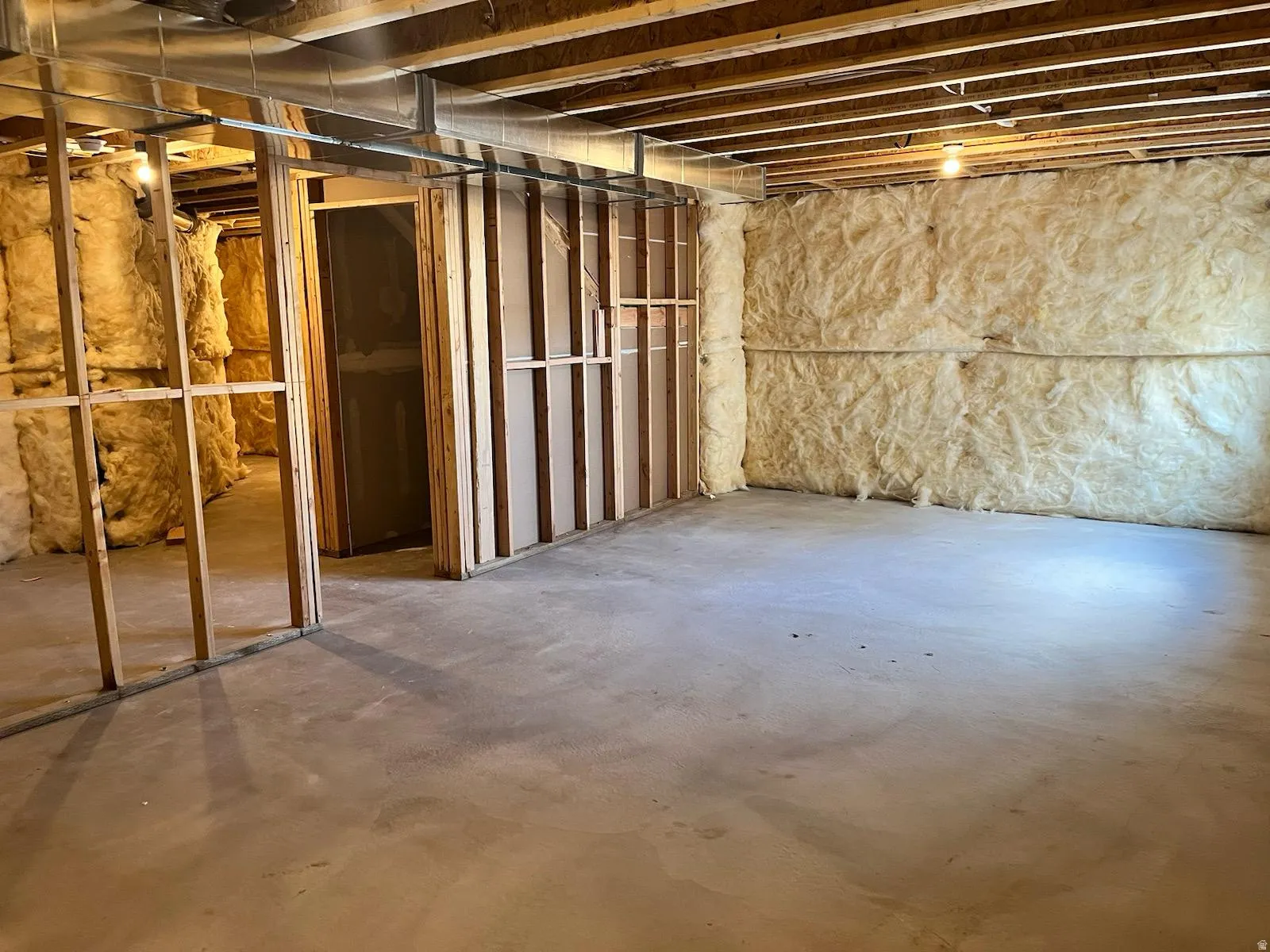 Unfinished lower level offering a concrete floor, exposed wood ceiling joists, and existing wall insulation