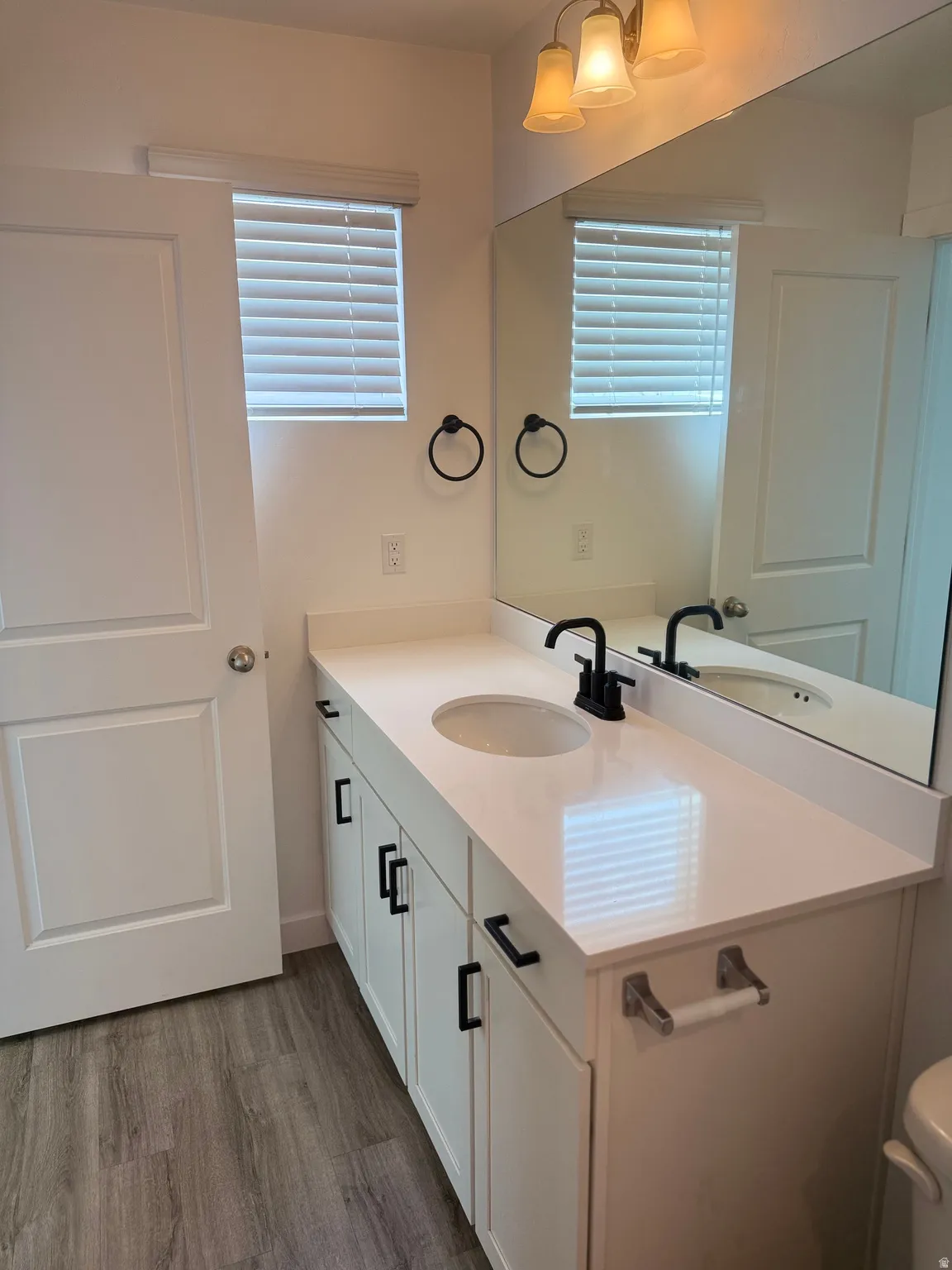 Bathroom featuring a single vanity with a white countertop, undermount sink, and matte black faucet