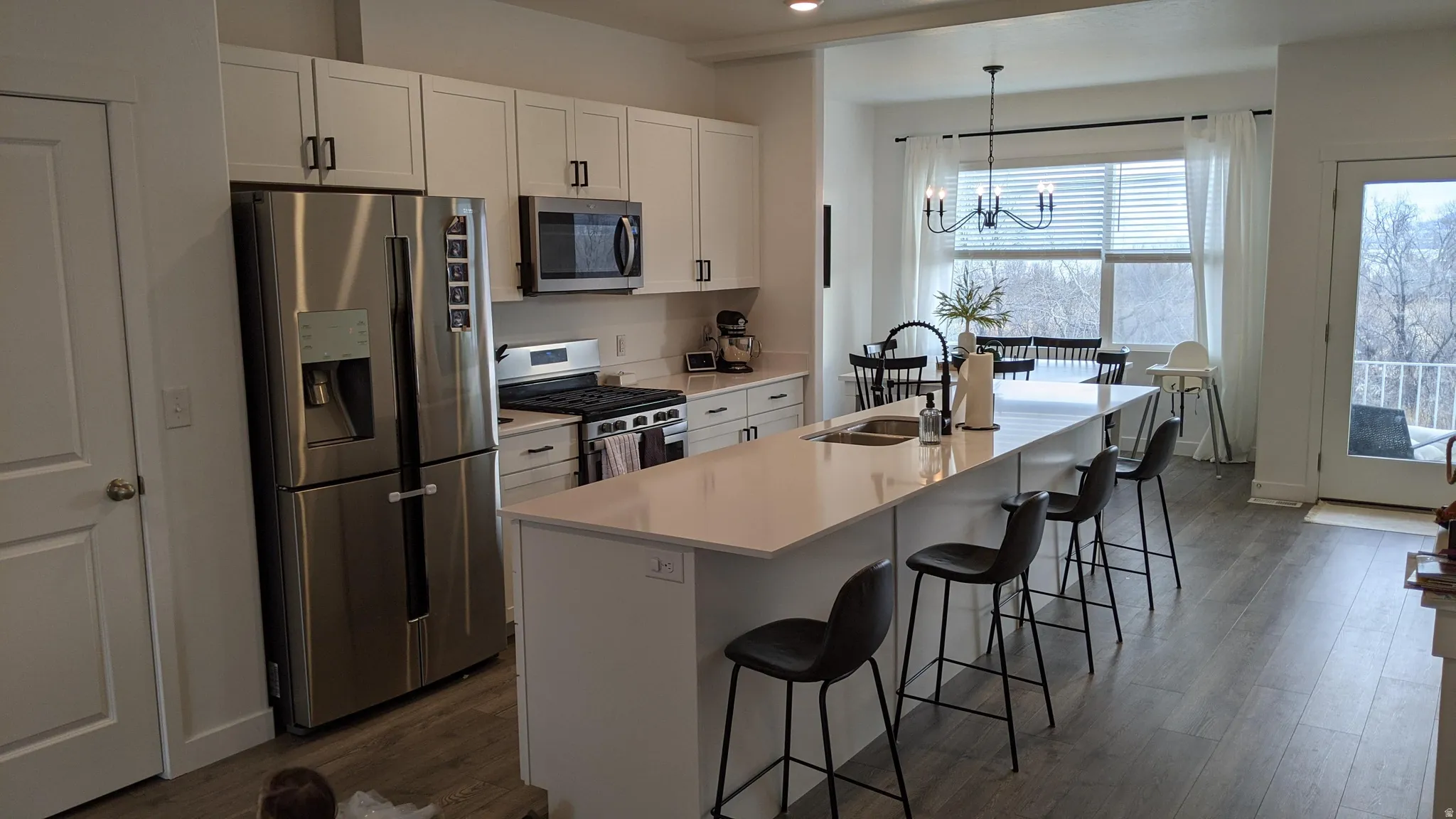 Bright kitchen featuring white cabinetry, stainless steel appliances, and a large central island with seating