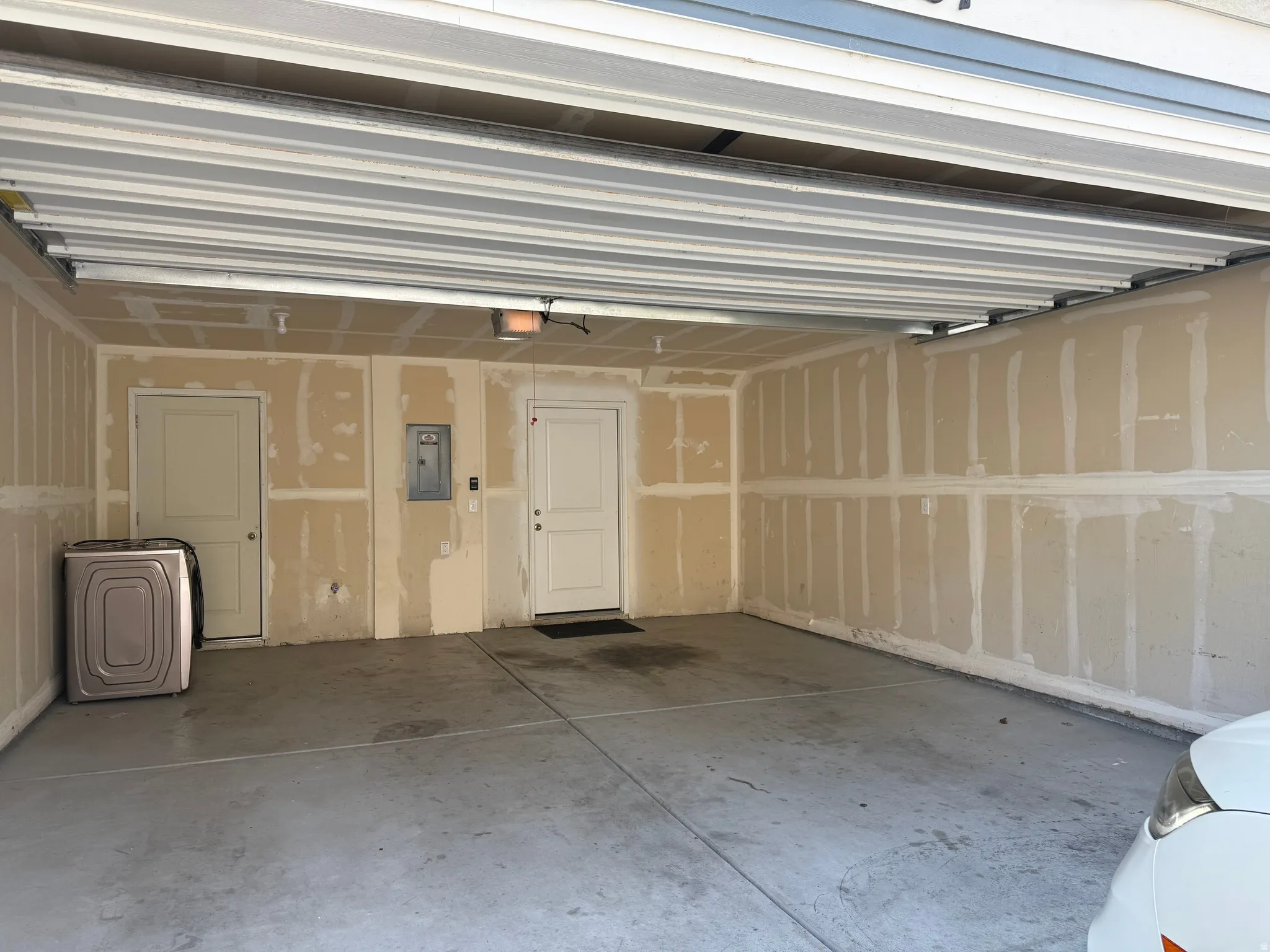 Spacious garage featuring a concrete floor, two interior access doors, and an exposed ceiling structure