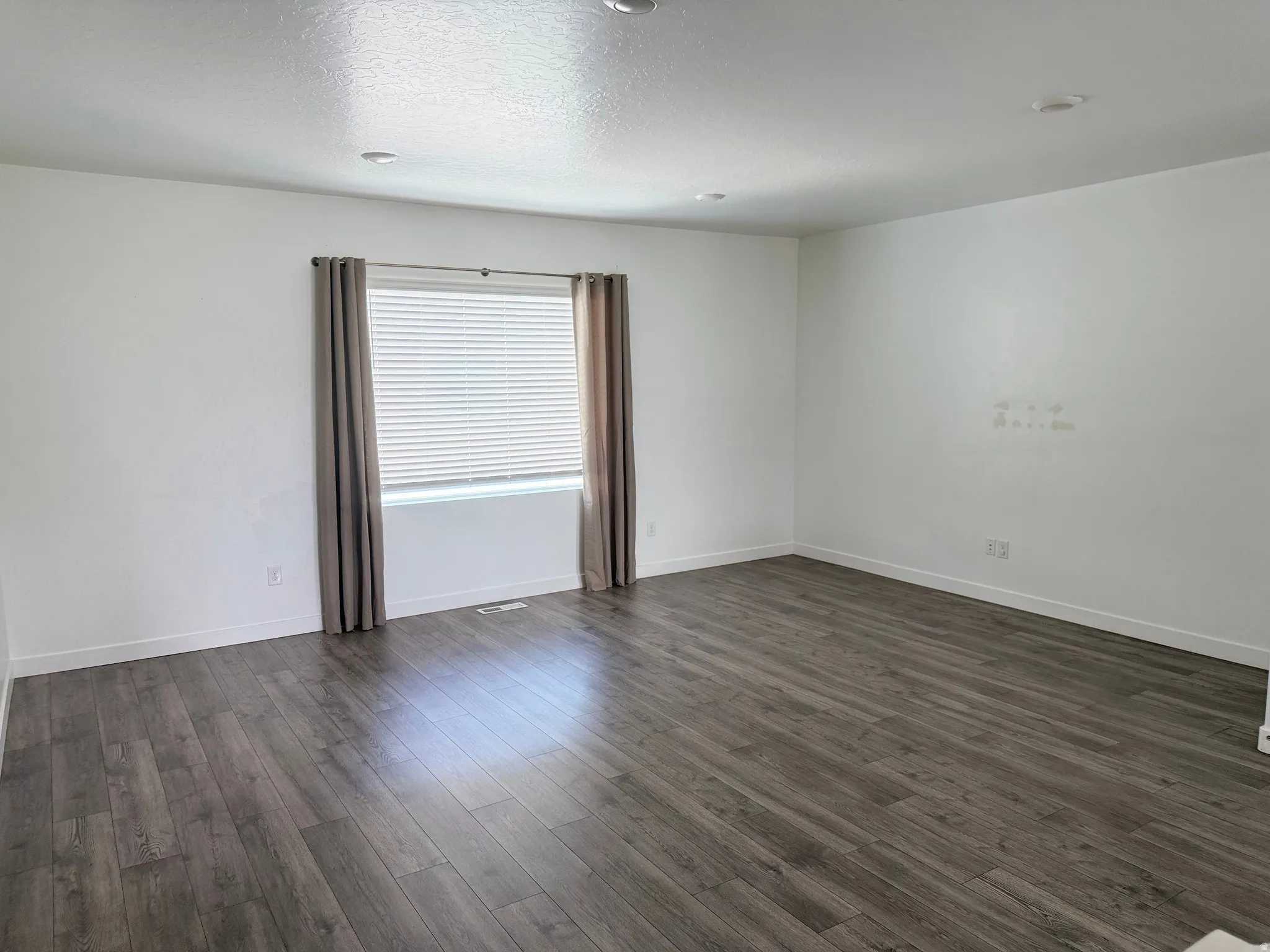 Spacious interior featuring wood-finish flooring, white baseboards, and neutral wall tones