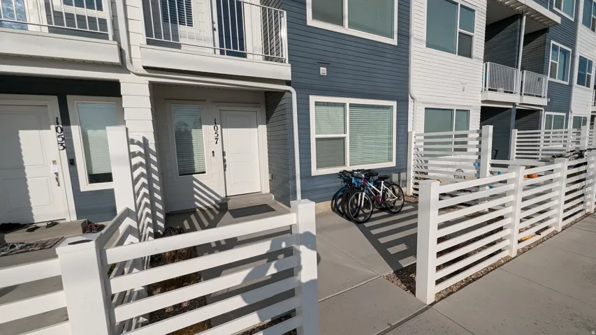 Multi-level residential building featuring a blue and white facade, ground-level entryways, and upper-story balconies with railings