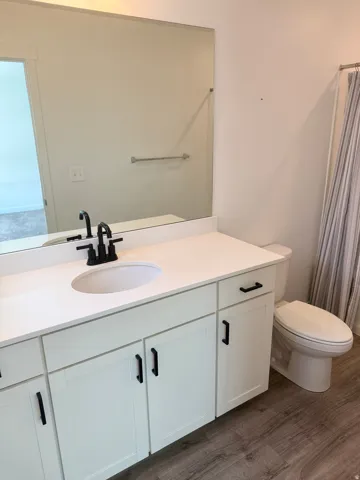 Bathroom vanity featuring an integrated sink, white cabinetry with black hardware, and a white countertop