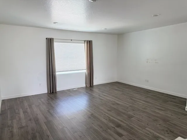 Spacious interior featuring wood-finish flooring, white baseboards, and neutral wall tones