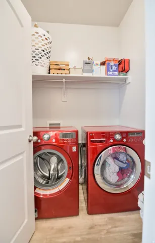 Dedicated laundry closet featuring a built-in shelf, white walls, and wood-finish flooring