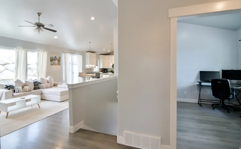 Open-concept living space featuring wood-finish flooring, a ceiling fan with integrated lighting, and recessed lighting
