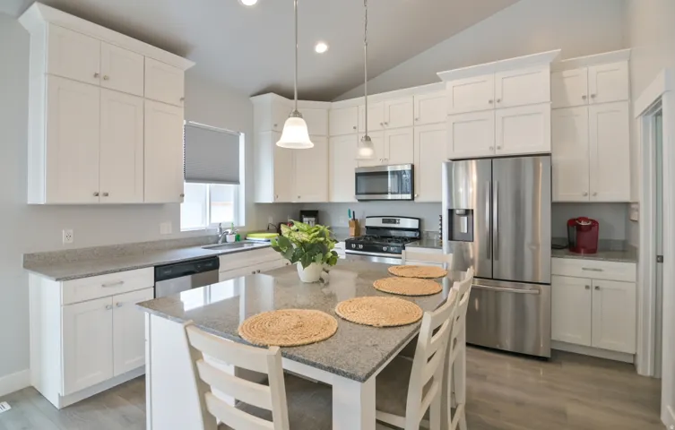 Open-concept kitchen featuring white cabinetry, granite countertops, and stainless steel appliances