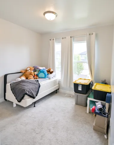 Light-filled room featuring neutral-toned carpeting, white walls, and a contemporary ceiling light fixture