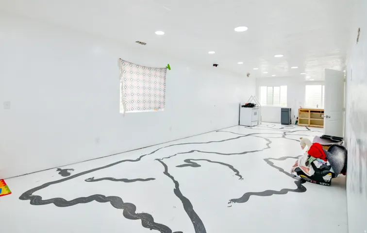 Spacious room featuring recessed lighting, multiple windows, white walls, and a white floor with a unique dark grey pattern