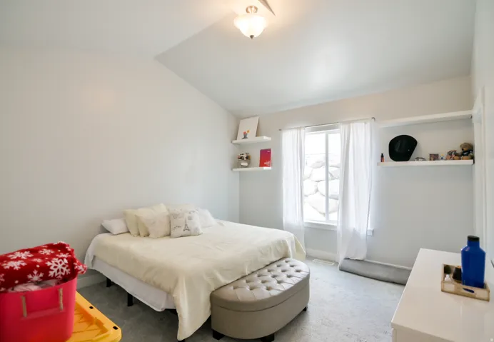 Bright room featuring white walls, carpeted flooring, a ceiling-mounted light fixture, and a window with white trim