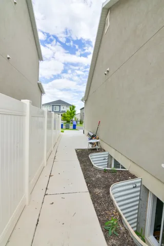 Concrete pathway with white vinyl fencing and two window wells