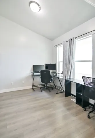 Spacious room featuring light wood-finish flooring, white walls, and a contemporary flush-mount ceiling light
