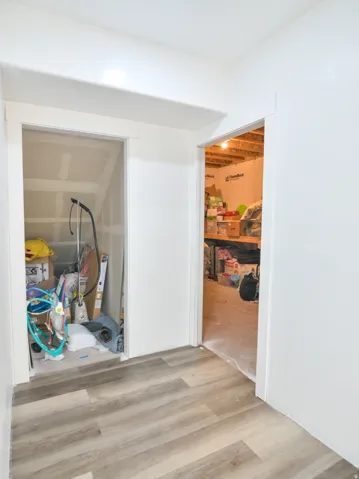 Hallway with light wood-finish flooring, white walls, and two open doorways