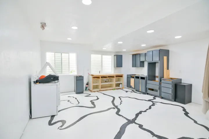 Spacious interior featuring recessed lighting, white walls, multiple windows with horizontal blinds, and existing cabinetry