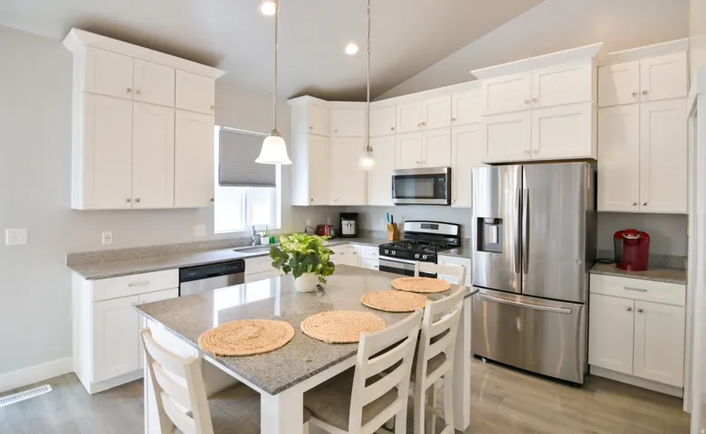 Kitchen featuring a central island with seating, white shaker-style cabinetry, stainless steel appliances, speckled stone countertops, and wood-finish flooring