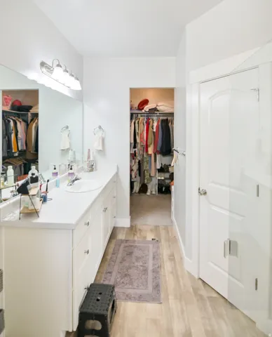 Spacious vanity area featuring an expansive countertop with an integrated sink, ample storage cabinetry, and wood-finish flooring