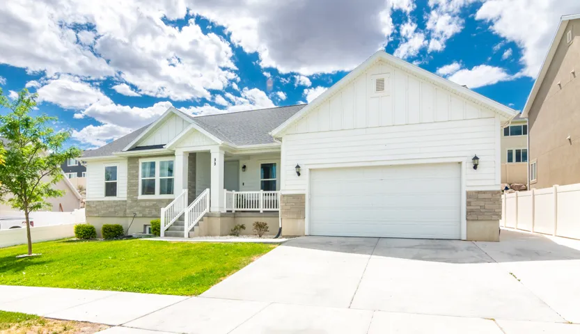 Contemporary single-story residence with a two-car garage, featuring white siding, stone veneer accents, a covered front porch with white railings, and a concrete driveway