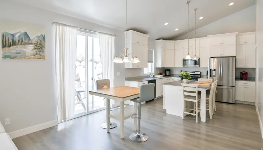 Modern kitchen featuring white cabinetry, stainless steel appliances, a center island with seating, and wood-finish flooring